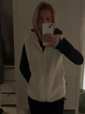 Vit fleeceväst med dragkedja - Mysig vit fleeceväst med hel dragkedja framtill och hög krage. Perfekt att slänga över en hoodie eller tröja för extra värme. Enkel och stilren design som passar till många outfits.