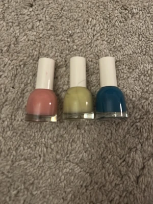 Nagellack trio från H&M - Tre snygga nagellack från H&M i olika färger: ett i mjuk rosa, ett i ljusgul och ett i klarblå. Flaskorna har rundad form och vita korkar. Perfekt för dig som gillar att variera din nagelstil med färgglada och trendiga nyanser.