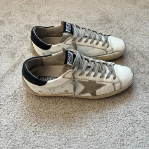 Golden Goose sneakers - Säljer dessa klassiska och tidlösa Golden Goose skorna med mörkblå häl! | Size: 42, sitter TTS. | Väldigt fint skick, dock är det två små skråmor på ena sulan (se bilder). Resten av slitningarna är design från fabrik | Bara skorna ingår. | Postar samma dag!📬| Skriv vid frågor & funderingar!