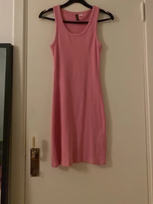Rosa ribbad klänning H&M Divided S - Säljer en rosa ribbad kortklänning från H&M Divided i storlek S. Klänningen är ärmlös med rund halsringning och har en slim passform. Perfekt för sommardagar och enkel att styla med sneakers eller sandaler.