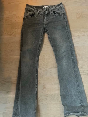 Gråa bootcut lowwaist jeans  - Säljer ett par grå jeans från Gina Young. Ena knappen på bakfickan har lossnat annars är de i jättebra skick!