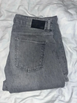 Grå bootcut jeans från 157, M short - Säljer ett par gråa bootcut jeans från 157 i storlek M short. Jeansen har klassisk femficksdesign, låg midja och dragkedja fram. Materialet är mjukt denim och färgen är snyggt tvättad grå. Perfekt för dig som gillar retrovibbar och bredare ben.