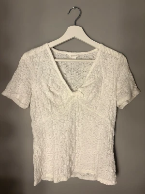 Vit spetsblus från Dobber - Säljer en vit blus från märket Dobber i storlek S som är köpt på MQ. Blusen har korta ärmar, v-ringad hals och är täckt av ett fint spetsmönster. Materialet är lätt och luftigt, perfekt för vår och sommar. Den är som ny och är använd några få gånger. (Den är inte genomskinlig)
