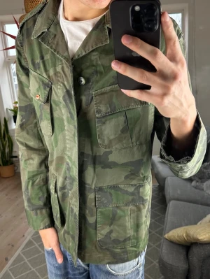 Fieldjacket Camo - Väldigt trendig och unik. Mycket bra skick, inga defekter. Skriv vid fundering! Mått: A:50 B:54 C:48 D:65 (cm) 😊🙌 (storlek 50~M) 