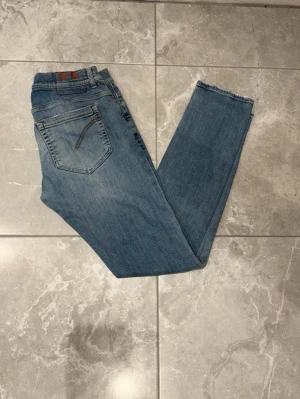 Dondup jeans - Ljusblå jeans från dondup, modell George och skinny fit. Jeansen har knappgylf och är tillverkade i mjuk bomullsdenim. Perfekta för dig som vill ha en stilren look. Storleken är i 33.