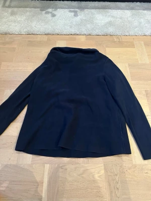 Mörkblå polotröja från COS, storlek S - Mörkblå polotröja från COS i storlek S. Tröjan har en enkel och stilren design med lång ärm och hög krage. 