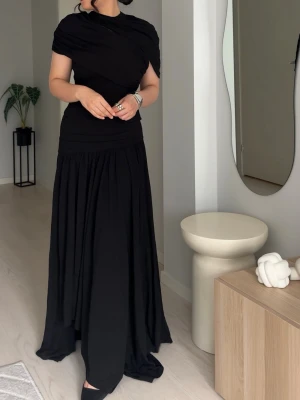 Svart långklänning med draperad topp - Säljer en svart långklänning med asymmetrisk, draperad topp och ett svepande, voluminöst kjolparti. Klänningen har kort ärm på ena sidan och är figurnära upptill med markerad midja. Perfekt för dig som gillar stilrena och dramatiska looks.