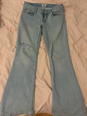Bootcut ljusblå jeans från lager 157 - Bootcut jeans i ljusblå tvätt från lager 157 med klassisk femficksdesign och dragkedja. Materialet är jeans och passformen är loose med låg-mid midja. Köpte de för 400kr. Jättesnygga, bara att de har ett hål på knät som jag gjort! 