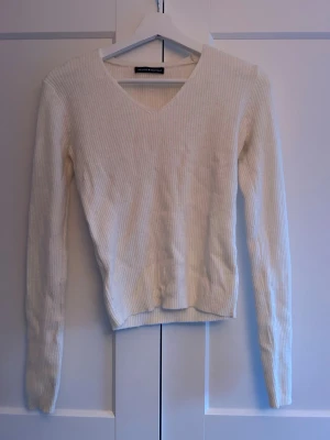 Tröja - Säljer en vit ribbad långärmad tröja från Brandy Melville med v-ringad hals. Tröjan är slim fit och har en mjuk, stretchig känsla. One size men skulle säga xs/s. 