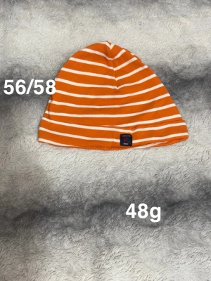 Randig orange mössa från Polarn O. Pyret - Säljer en snygg orange mössa med vita ränder från Polarn O. Pyret. Mössan har en klassisk form. Märkeslapp framtill. Passar dig som gillar färg och stil!🌸 Fint använt skick. Storlek 56/58