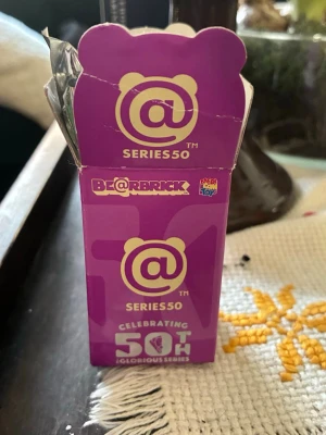 Grå Death Stranding 2 Be@rbrick väst - Säljer en unik väst till Be@rbrick figur från Death Stranding 2-kollektionen, Series 50. Västen är grå med detaljer i orange och svart, och har tryck inspirerat av spelet. Perfekt för samlare som gillar gaming och cool design.