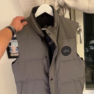 Garson vest Canada Goose black label  - Dunväst från vanda goose. ”Garson vest” z. I princip oanvänd. Storlek M. Färgen coastal grey. Fjädrar och dun från anka. 