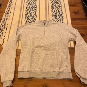 Grå half zip sweatshirt från NLY Trend - Ljusgrå sweatshirt från NLY Trend i storlek S. Tröjan har en hög krage och half zip-dragkedja framtill. Tillverkad i mjuk bomullsblandning med långa ärmar och ribbade muddar vid ärmslut och nederkant. Perfekt för en chill och avslappnad stil.