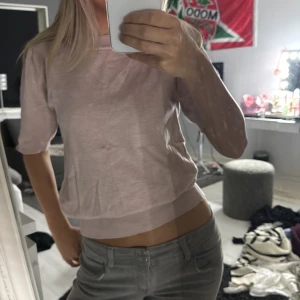 Ljusrosa kortärmad topp - Säljer en ljusrosa topp med korta ärmar och rund hals. Toppen har en enkel och clean design med ribbad kant nedtill och vid ärmsluten. Perfekt att matcha med jeans eller kjol för en chill look.