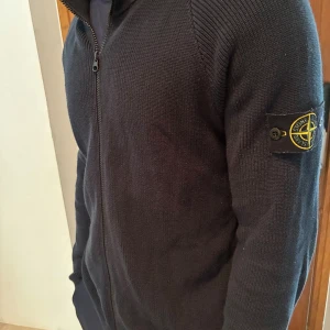Mörkblå Stone Island kofta  - Snygg mörkblå stickad kofta från Stone Island med dragkedja framtill och patch på vänster ärm. Storlek: M