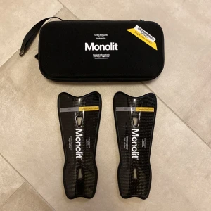 Benskydd Monolit i kolfiber - Hej! Säljer ett par svarta benskydd från Monolit i kolfiber med snygg, modern design. Det är en av världens lättaste beskydd och har en formad passform för extra komfort. Kommer med ett praktiskt svart fodral med dragkedja och handtag. Perfekta för dig som vill ha stilrena och lätta benskydd på planen! Nypris: 789 kronor. Fjäderlätta och sköna! Tveka inte att höra av dig vid frågor.