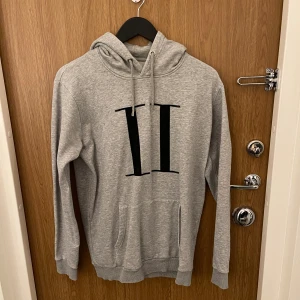 Grå hoodie från les deux - Snygg grå hoodie med stor svart romersk siffra II på bröstet. Tröjan har huva med snörning och en klassisk känguruficka framtill. Perfekt för en avslappnad och trendig stil.