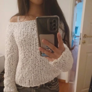 Vit offshoulder stickad tröja - Supermysig vit stickad tröja med offshoulder-modell och lång ärm. Tröjan har en chunky, bubblig struktur som gör den extra gosig och unik. Perfekt att styla med jeans eller kjol. Använd en gång.🤍