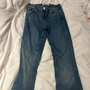 Blå jeans  - Klassiska blå jeans med raka ben och femficksmodell. Jeansen har normalhög midja, dragkedja och knapp framtill samt bälteshällor. Tillverkade i jeansmaterial med en snygg tvättad finish. Perfekta för en avslappnad och stilren look.
