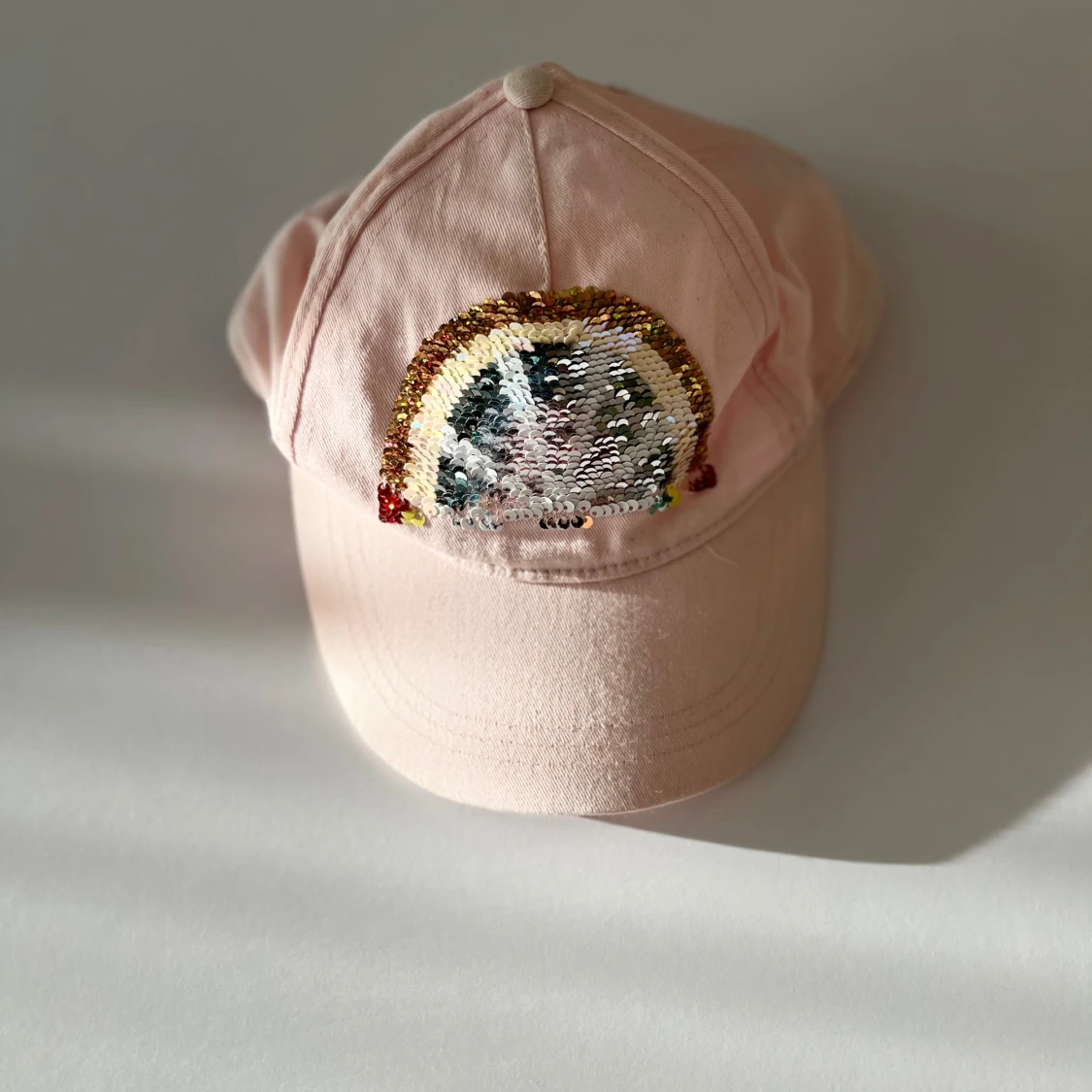 Rosa keps med paljettregnbåge från H&M