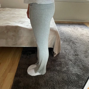 Ljusgrå mjukisbyxor med bootcut - Superbekväma ljusgrå mjukisbyxor med bootcut och hög midja. Byxorna är i mjukt och stretchigt material, perfekta för en chill dag hemma eller när du vill ha en avslappnad look. Sitter tajt upptill och släpper ut vid benen.
