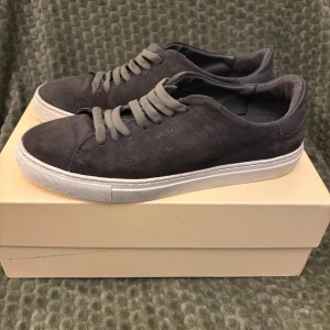 Axel Arigato strlk 42, Grå mockasneakers - Snygga sneakers från Axel Arigato i mörkgrå mocka. Perfekta för dig som gillar stilrena och minimalistiska sneakers. Bra/Okey skick men inte trasiga, ett litet märke fram på ena sulan, se bilder. Skorna har mycket kvar att ge! Skriv gärna om du undrar något eller vill ha fler bilder!  Mvh Mimmi 