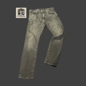 Grå jeans från Polo Ralph Lauren - Snygga grå jeans från Polo Ralph Lauren med klassisk femficksdesign och svarta läderdetaljer på bakfickan. Jeansen har rak passform och är tillverkade i slitstarkt denim. Perfekta för dig som gillar en stilren och avslappnad look. Nypris: 2000kr