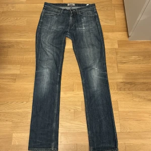 Acne Studios blå raka jeans - Snygga blå jeans från Acne Studios i klassisk rak modell. Jeansen har en tvättad look med diskreta slitningar och femficksdesign. Tillverkade i bomull för en skön känsla och stilren passform. Perfekta för dig som gillar en tidlös och avslappnad vibe.