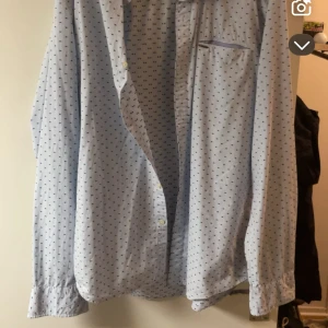 Ljusblå mönstrad skjorta Scotch & Soda - Snygg ljusblå skjorta från Scotch & Soda med diskret prickigt mönster i mörkblått. Klassisk krage, långärmad och med knappar framtill. Perfekt för dig som gillar stilrena detaljer och vill ha något som sticker ut lite extra.