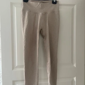 Beige ribbade leggings från Aim'n - Snygga beige leggings från Aim'n med ribbad struktur och hög midja. De är stretchiga och sitter tight, perfekta för en chill look eller till träning. Materialet är mjukt och följsamt, och färgen är lätt att matcha med det mesta. Enda defekten är att metallmärket på byxan har lossnat på ena sidan 