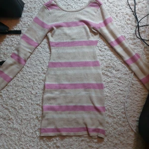 Randig stickad klänning - Bubbleroom - Supersöt stickad kortklänning från Bubbleroom i beige och rosa med breda ränder. Klänningen har lång ärm, rund halsringning fram och djupare rygg. Perfekt för dig som gillar en slim passform och vill ha något bekvämt men ändå snyggt.