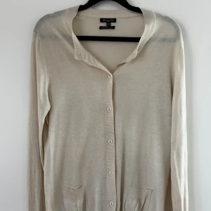 Beige kofta Massimo Dutti - Snygg beige kofta från Massimo Dutti i lyxig blandning av silke och kashmir. Klassisk modell med knappar framtill, två fickor och lång ärm. Perfekt för lager-på-lager och stilrena outfits.