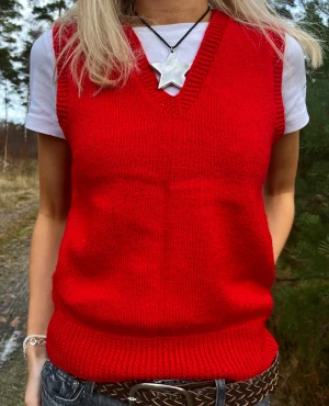 Röd stickad vest  - Snygg vibrant röd vest! Gissar på att den är egengjord då märke och storlek saknas! Modellen brukar bära S. 