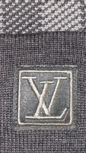 Grå rutig mössa Louis Vuitton - Snygg grå mössa från Louis Vuitton med klassiskt rutigt mönster och uppvikt kant. LV-logga i silver på framsidan ger en lyxig touch. Materialet är mjukt och stickat, perfekt för kyliga dagar. Passar dig som vill ha en stilren och exklusiv look.