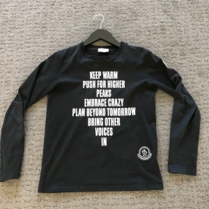 Svart långärmad Moncler tröja - Säljer en svart långärmad tröja från Moncler. Den är i mycket bra skick. Tröjan har en snygg text i vitt. Moncler loggan finns nere till vänster på framsidan och på vänster arm i vitt. Tröjan har en QR-kod på en lapp som man kan skanna. Tröjan passar allt från 152-160.