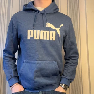 Blå hoodie från Puma  - Blå hoodie från Puma i storlek M med stor vit Puma-logga på bröstet. Tröjan passar även storlek Small eftersom den är lite mindre i storleken. Tröjan passar perfekt till casual och grisch stilen!