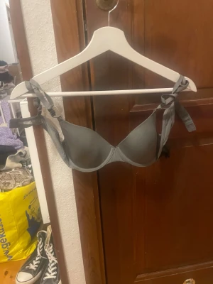 Grå linnetopp från H&M  - Snygg grå linnetopp från H&M i storlek 75B. Toppen har vadderade kupor. Materialet är mjukt och skönt, perfekt för att bära under andra plagg eller som statement piece. Enkel och stilren design.