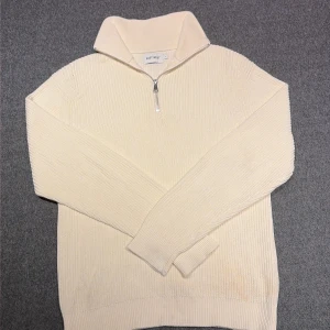 Vit stickad half zip-tröja East West - Säljer en vit stickad tröja från East West i storlek S. Tröjan har en hög krage och half zip-dragkedja framtill. Ribbstickad struktur och långärmad modell som ger en clean och chill look. Perfekt för lager-på-lager under kyliga dagar.