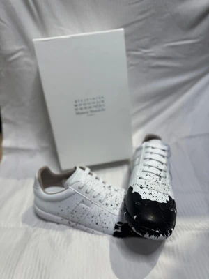 Maison Margiela svartvit sneakers - Säljer ett par Maison Margiela sneakers i fint skick. Kommer med box, pris kan diskuteras vid snabb affär. 