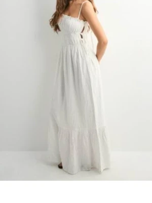 Vit långklänning med smala axelband - Långklänning i vitt med smala axelband och lätt rynkad midja. Klänningen har en luftig passform och är tillverkad i ett tunt, somrigt material. Perfekt för varma dagar och har en enkel men elegant look.