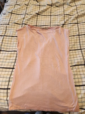 Ljusrosa ärmlös topp från 157 - Säljer en enkel och stilren ljusrosa topp från 157. Toppen är ärmlös och har en rak, loose passform. Tillverkad i mjuk bomull som känns skön mot huden. Använd ca 3ggr. Nypris: 200kr