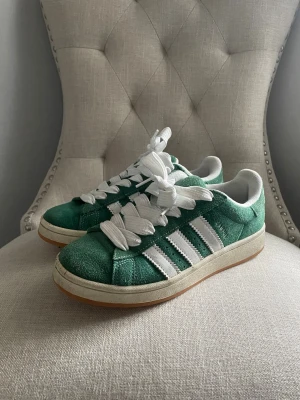 Gröna Adidas Campus 00s - Säljer nu mina adidas campus, skönaste skorna men kommer inte till användning. Köptes för ca 3 år sen o är fortfarande i perfekt skick både in och utvändigt förutom all smuts. I storlek 39 1/3, passar mig som har strl 38-39. Kan tvättas innan jag postar!🫶🏼