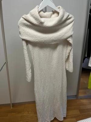 Vit lång stickad klänning H&M - Mysig vit långklänning från H&M med grovstickad struktur och bred polokrage som kan bäras offshoulder. Klänningen har lång ärm och är perfekt för kyligare dagar. Materialet känns mjukt och omfamnande.