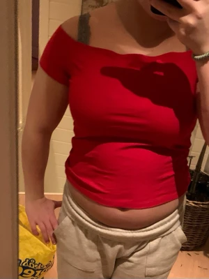 Röd off shoulder topp - Trendig röd off shoulder topp med korta ärmar och figurnära passform. Perfekt att styla med både jeans och kjol för en snygg look. Tillverkad i mjukt stretchigt material som sitter skönt på kroppen.