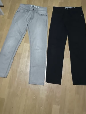 Två par jeans från Indicode, 28/30 - Säljer två par raka/slim fit jeansen från Indicode, ett par i ljusgrått och ett par i svart. Klassisk femficksmodell med knapp och dragkedja. Perfekta för dig som gillar enkel och stilren look.    Priset gäller båda jeansen❗️