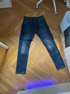 Levi's 512 mörkblå jeans herr - Snygga mörkblå Levi's 512 jeans med klassisk femficksdesign och raka ben. Jeansen har en slim passform och är tillverkade i slitstarkt bomullsdenim. Perfekta för dig som gillar en tidlös och clean look. Storlek 32 32. Pris kan diskuteras.