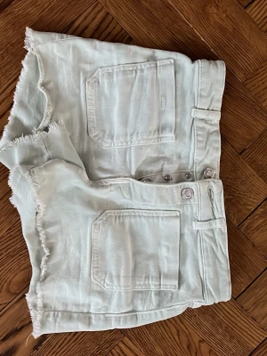 Ljusgröna somriga shorts med fransar 💚 - Snygga gröna jeansshorts med hög midja och råa, fransiga kanter. Shortsen har stora fickor fram och bak samt knappar i midjan. Perfekta för sommaren och lätta att matcha med allt.❤️