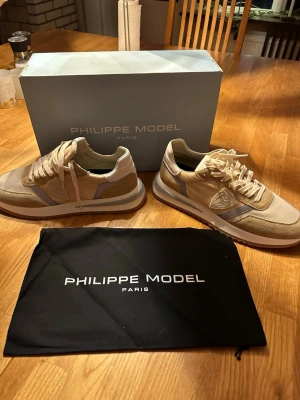 Philippe Model tropez 2.1 - Säljer ett par Philippe Model Tropez 2.1 Low Man sneakers i beige med vita och ljusblå detaljer. Skorna har en klassisk siluett, mesh och mocka-paneler samt vita snören. Kommer med originalkartong och dustbag. Perfekta för dig som gillar stilrena och exklusiva sneakers. Helt nya ! Säljer då de inte passar nypris 3695kr