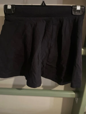 Svarta vida shorts med hög midja - Säljer ett par svarta shorts med hög midja och vid passform. De har en bred linning upptill och är tillverkade i ett mjukt bomullsliknande material. Perfekta för en avslappnad och stilren look.