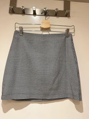 Svart och vit minikjol från Gina Tricot - Elegant minikjol i svart och vitt mönster från Gina Tricot. Kjolen har en dragkedja baktill. Passar perfekt att både klä upp och ner.